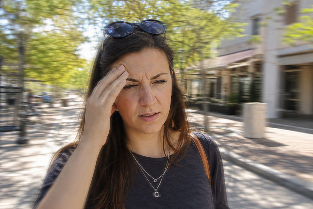 Woman squinting outdoors in daylight, representing blurry vision and common astigmatism treatment options.
