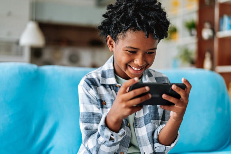 Young boy playing on a handheld device, illustrating how screen time affects your eyes in a screen-heavy lifestyle.