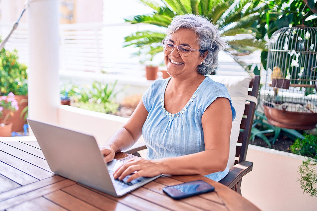 Smiling woman using a laptop to schedule cataract surgery in Lubbock