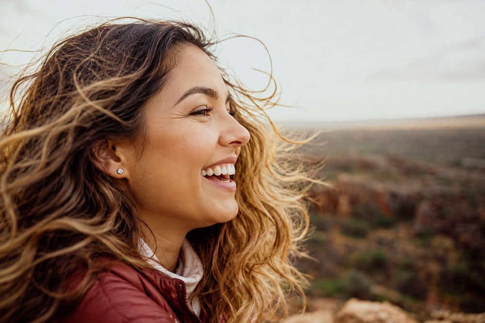 Smiling woman enjoying clear vision outdoors after PRK eye surgery recovery.